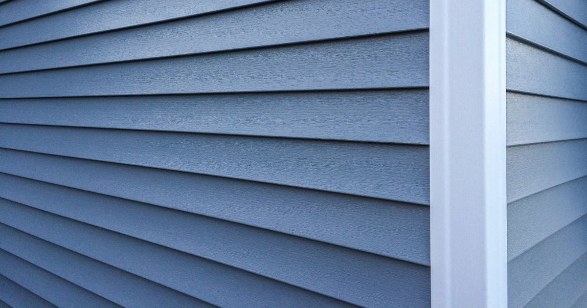 Professional blue vinyl siding installation on residential home